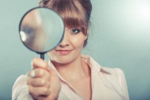 portrait of woman looking through a magnifying glass