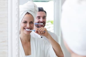 happy man and woman brushing teeth in the bathroom