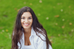 smiling young woman sitting on green grass outside