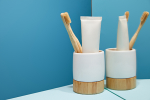 toothbrush and toothpaste in white cup on countertop