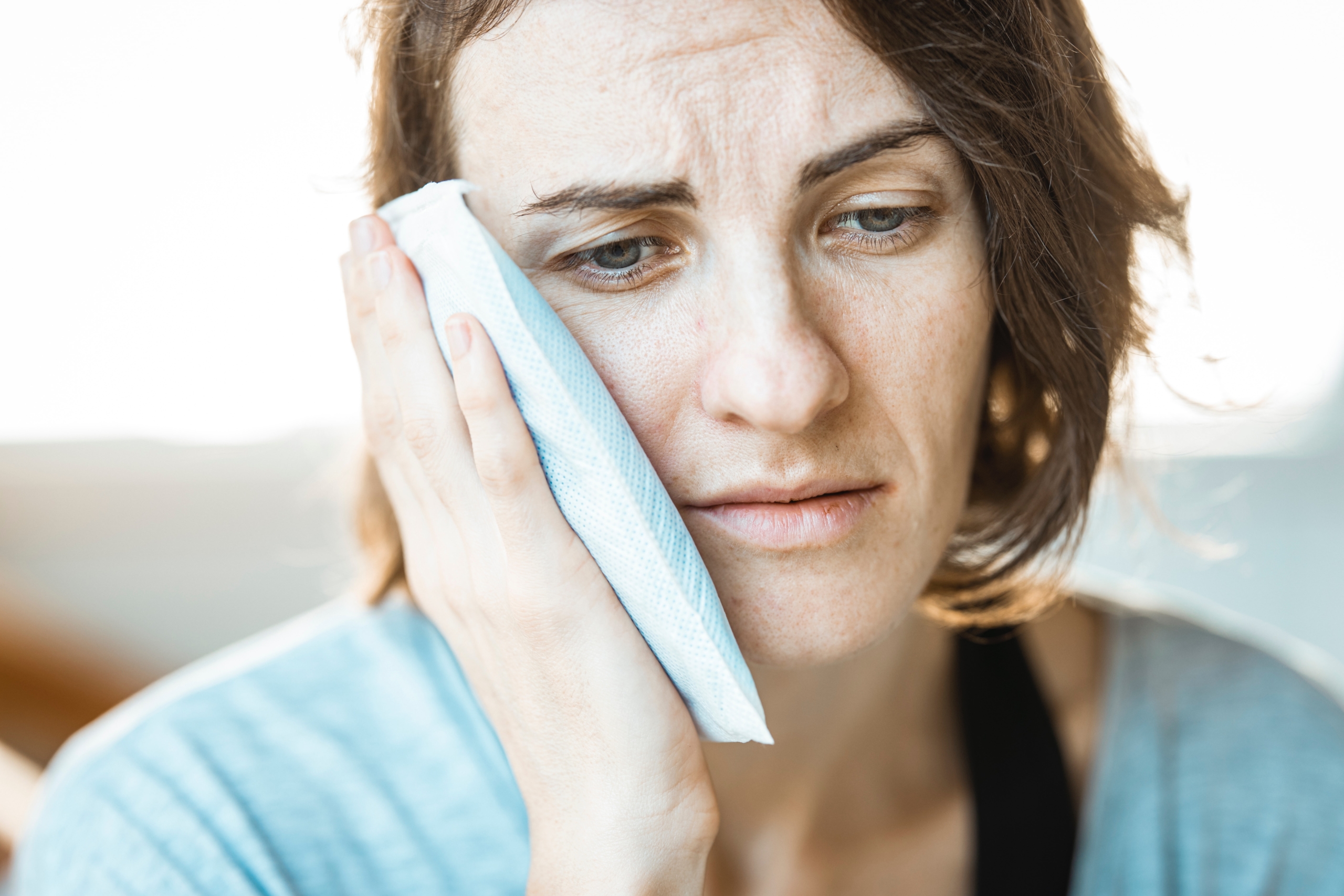 woman holding her face because it is sore and needs to visit TMJ dentist in denver