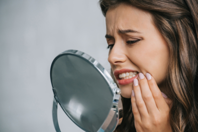 woman looking at tooth in mirror