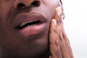 close up of black man touching the face in pain