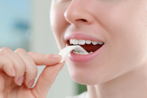 young woman placing a piece of gum in her mouth