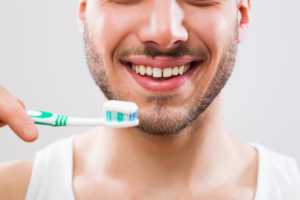 close up of man holding toothbrush with toothpaste up to his mouth