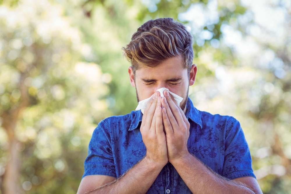 man blowing his nose outside